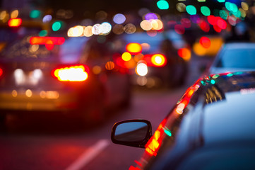 Rear mirror of a car parked next to road with busy traffic