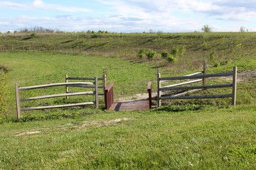 Fototapeta na wymiar The wood fence and bridge in the green grass field.