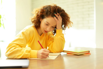 Beautiful girl writing in notebook in cafe