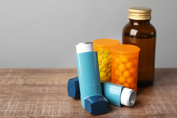Asthma inhalers with medicines on wooden table