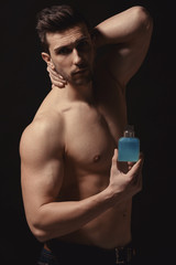 Handsome man using perfume on black background