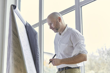 Fototapeta premium Bald Businessman Looking Carefully at the Board