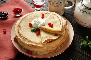 Tasty pancakes with cream and berries on table