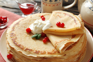 Tasty pancakes with cream and berries on table