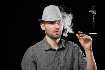 Handsome man smoking cigarette on dark background