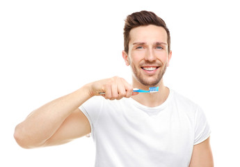 Young handsome man brushing teeth on white background