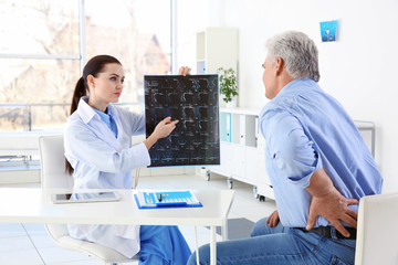 Obraz premium Female orthopedist examining senior man in clinic