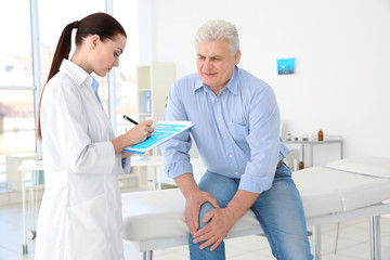 Female orthopedist examining senior man in clinic