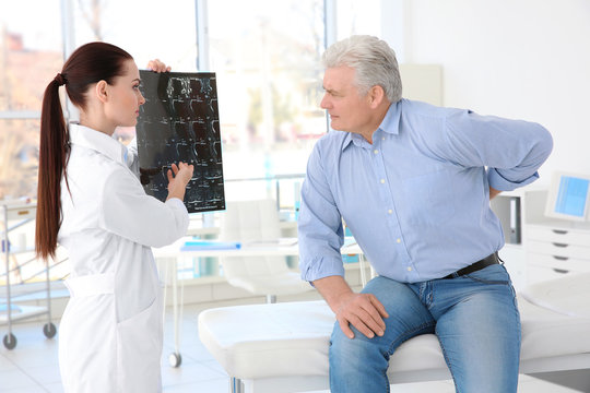 Female orthopedist examining senior man in clinic