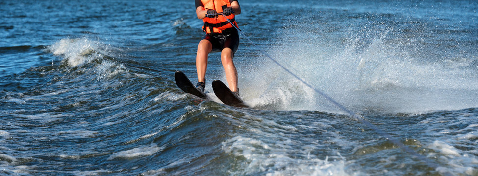 Woman riding water skis closeup. Body parts without a face. Athlete water skiing and having fun. Living a healthy lifestyle and staying active. Water sports theme. Summer by the sea. Banner for