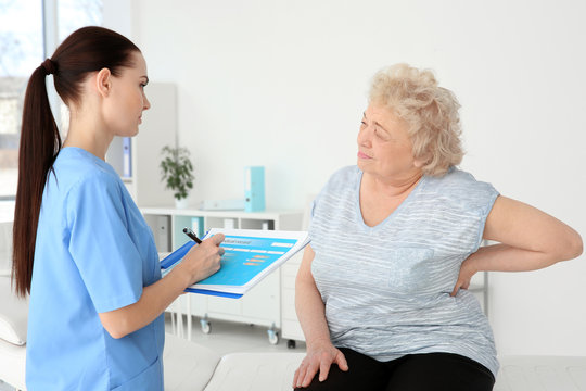 Female orthopedist examining senior woman in clinic