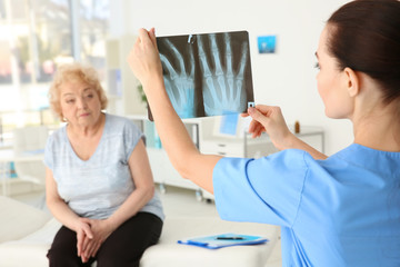 Obraz premium Female orthopedist examining senior woman in clinic