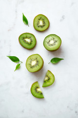 Kiwis flat lay on a marble background. Group of sliced and whole kiwi fruits viewed from above. Top...