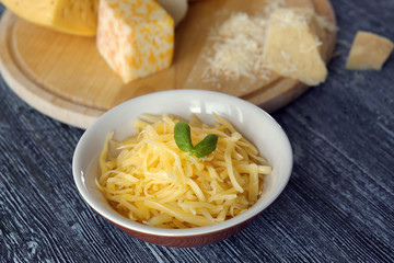 Bowl with grated cheese on wooden table
