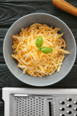 Bowl with cheese and grater on wooden table