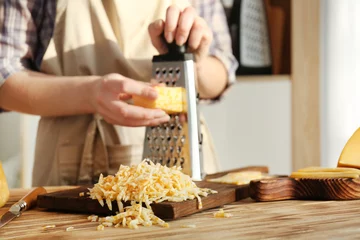 Foto op Aluminium Woman grating cheese on wooden table © Africa Studio