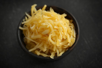 Bowl with grated cheese on table
