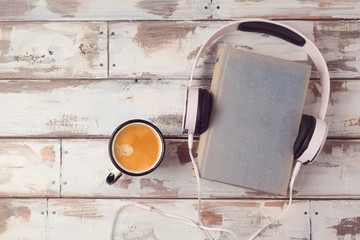 Audio book concept with old book, headphones and coffee cup. View from above. Flat lay