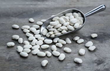 Metal scoop with beans on grey wooden table