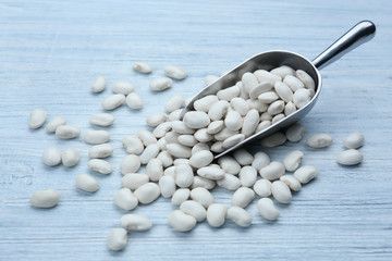 Metal scoop with beans on wooden table