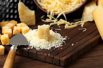 Cutting board with grated cheese on wooden table