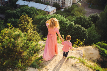 View from above - full body back view of mother with son standing on the hill