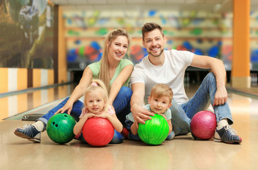 Fototapeta na wymiar Happy family sitting on floor in bowling club
