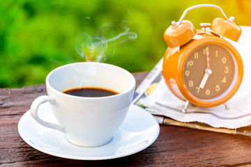 coffee cup clock and news paper on old wooden table