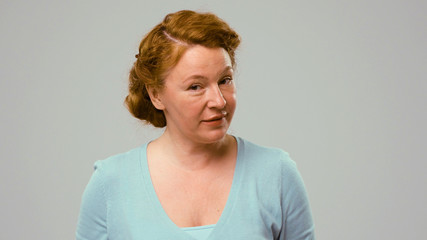 Mid aged actress showing emotions of mistrust. Actress in studio with white background shows the emotion of mistrust. Actress with curly red hair shows mistrust emotion.