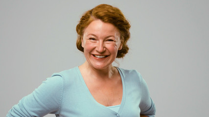 Mid aged positively smiling actress. Red-haired mid aged woman in studio with white background...