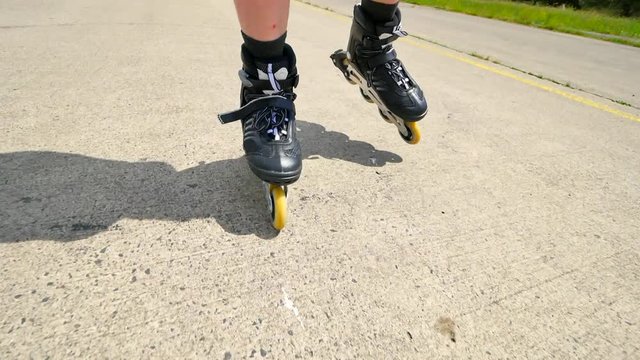 Mans legs roller skating on the asphal. Close up view to quick movement of inline boots.
