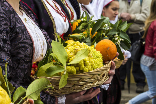 MURAVERA, ITALIA - APRILE 2, 2017:  45^ Sagra degli agrumi - dettaglio di un cesto di agrumi tenuto in mano da una donna in costume tradizionale sardo - Sardegna