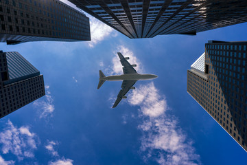 Fototapeta na wymiar Commercial airplane flying over modern building in Singapore city