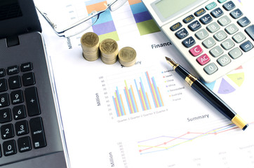 Financial concept with money coins stack and business fountain pen and calculator and eyeglasses and labtop with document chart on desk office backgrounds