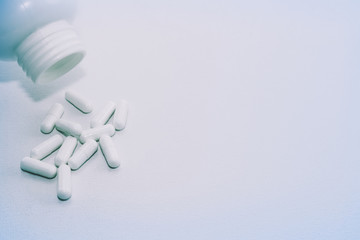 A medical background image consisting of a white pill bottle and white pills.