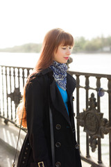 Beautiful red-haired young woman walking down the city street on a sunny day, examining the...