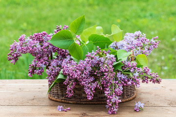 wicker basket with beautiful bouquet of lilac in garden