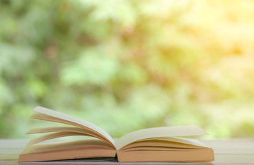 Open book on white table with nature background