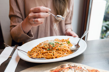 girl eats Italian pasta with tomato, meat. Close-up spaghetti Bolognese wind it around a fork with...