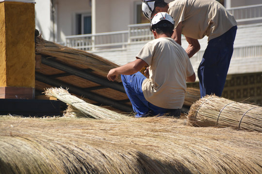 obreros reparando un tejado de paja