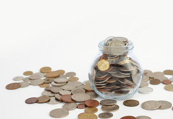 Overflowing jar of International coins on white background with copy space.