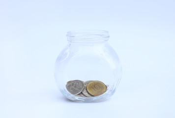 International coins in a glass jar on white background with copy space.