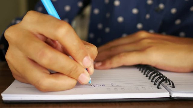 Female hands with pen writing on notebook.