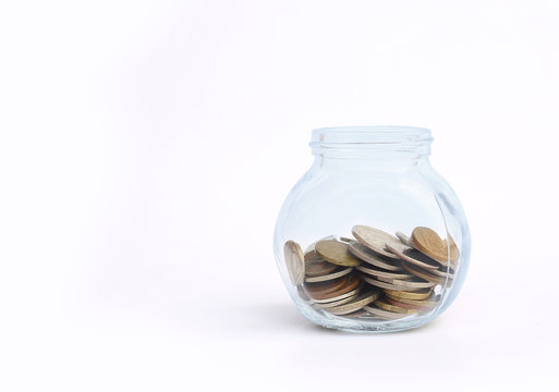 International coins in a glass jar on white background with copy space.