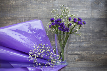 Flower bouquet in vase and purple packing paper