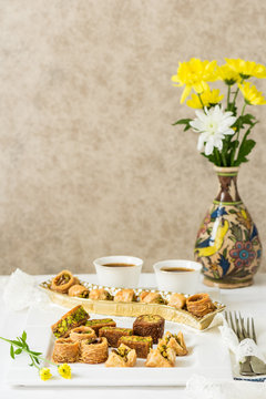 Assorted baklava- A Turkish sweet arranged on a decorative plate, with arabic black coffee cup in the background. Middle eastern food photography.