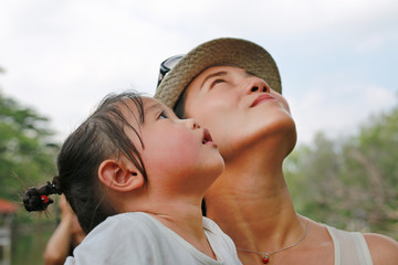 Portrait of Kid girl with young mother. Look up.