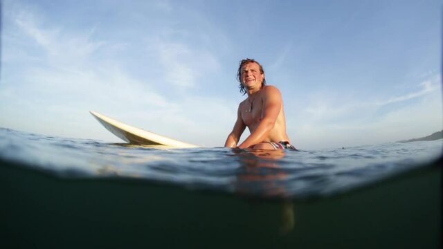 Young man with surf board waits the wave in the ocean