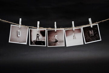 Rows of DREAM letters photo frames hanging with clothespins on dark background