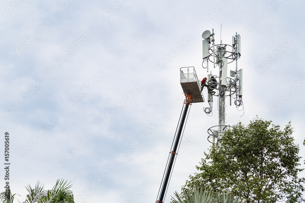 Wall mural two workers on crane installing mobile network telecommunication antenna